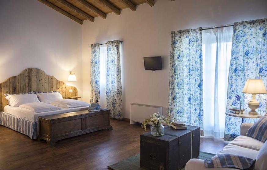 Camera accogliente con letto matrimoniale, arredi in legno e tende floreali.